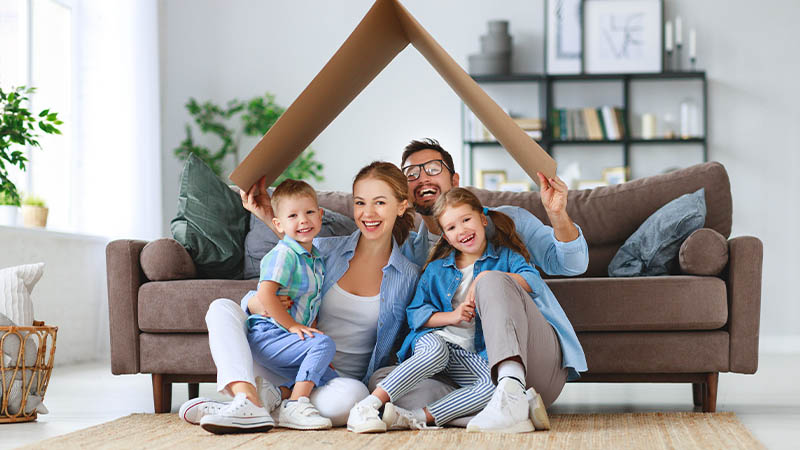 moving companies cedar rapids happy family sitting on the floor using a box as a fake roof