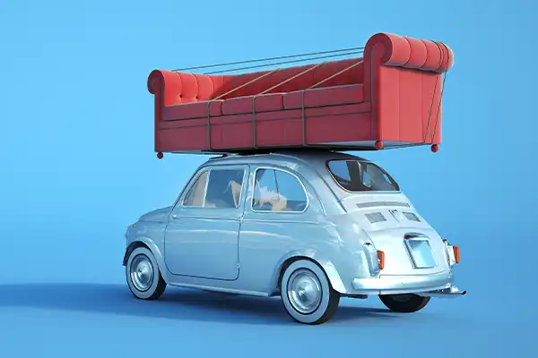 old bug car with a couch tied to the top of it, illustrating a small single item furniture moving job
